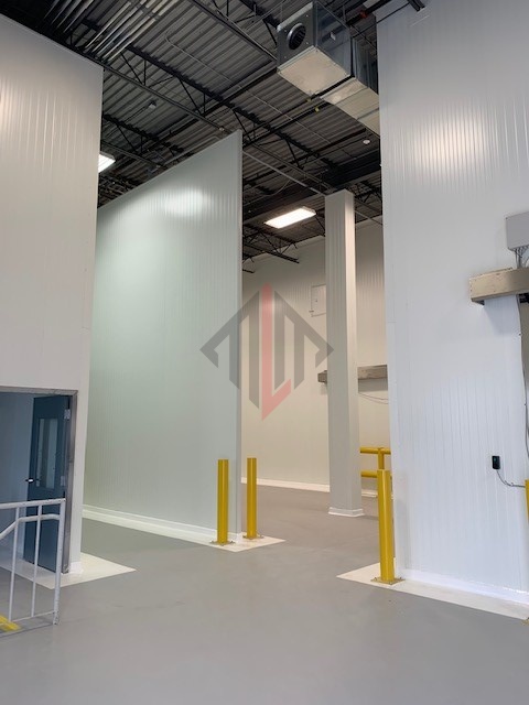 Indoor industrial space with white walls and yellow safety bollards.